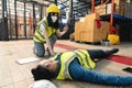 A female warehouse worker using a walkie-talkie called the factory& x27;s first aid team to rescue an unconscious man Royalty Free Stock Photo