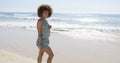 Female wearing jumpsuit walking along beach Royalty Free Stock Photo