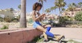 Female wearing rollerskates sitting on curb