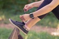 Female wearing smart watch and tying shoelaces in the park Royalty Free Stock Photo