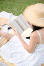Female in white dress, reading novel book while enjoying picnic in backyard