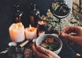 Female wiccan witch holding grey clay pot in her hands preparing ingredients for a spell at her altar