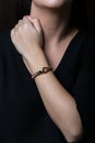 Female, wicker, bracelet from rose gold with carabiner in the middle on woman hand, on black background Royalty Free Stock Photo