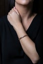 Female, wicker, bracelet from rose gold with diamonds in the middle on woman hand, on black background Royalty Free Stock Photo