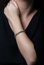 Female, wicker, silver bracelet with diamonds in the middle, on hand, on black background