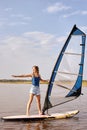 Female windsurfer at lake. Beautiful landscape. Summer water sports activities