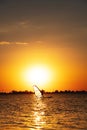female windsurfer silhouette at lake sunset. Beautiful beach landscape. Summer water sports activities, recreation and