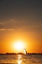 female windsurfer silhouette at lake sunset. Beautiful beach landscape. Summer water sports activities, recreation and