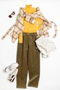 Female winter or autumn stylish clothing set. Plaid checkered shirt, yellow sweater, green corduroy trousers, sneakers and