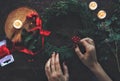 Female woman hands making DIY Yule winter solstice Christmas wreath from cedar evergreen tree branches.