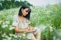 Female woman with pen writing or painting, handwriting on notebook on flower blooming meadow