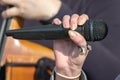 Female, woman singer hand with microphone close up, the trombone amd a musician hand on background