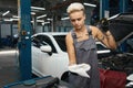 Female in work overalls checks the oil level in car