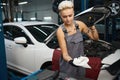 Female in work overalls wipes the dipstick to check the oil level in the car