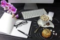 Female work space with computer, orchid, coffee and notebook with glasses and pen on black background. Royalty Free Stock Photo