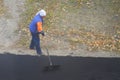 Female worker during asphalting road. Heavy female manual labor in construction