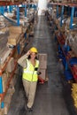 Female worker carrying cardboard boxes on pallet jack in warehouse Royalty Free Stock Photo
