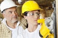 Female worker cutting wood with a power saw while male worker standing behind Royalty Free Stock Photo