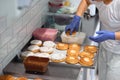 A female worker dips the donuts in a delicious topping in a candy workshop. Pastry, dessert, sweet, making