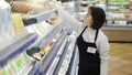 Female worker with Down syndrome restocking goods in a grocery store