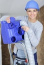 Female worker fitting ventilation hose into roof space