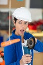 female worker holding angle-grinder looks in surprise at dangling carrot