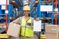 Female worker holding cardboard box and clipboard in warehouse Royalty Free Stock Photo