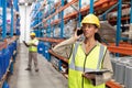 Female worker holding clipboard and talking on mobile phone in warehouse Royalty Free Stock Photo