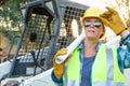 Female Worker Holding Technical Blueprints Near Small Bulldozer