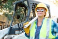 Female Worker Holding Technical Blueprints Near Small Bulldozer