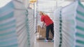 Female worker puts printed magazines in a box through the paper stacks