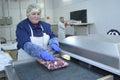 Female worker putting pieces of raw meat into vacuum bag. Packing shed of the slaughterhouse