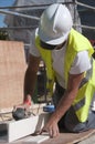 Female worker sanding wood with helmet