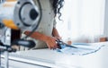 Female worker is in the sewing factory at daytime cutting cloth with scissors