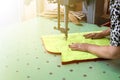 Female worker on a sewing manufacture uses electric cutting fabric machine. Royalty Free Stock Photo