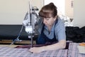 Female worker on a sewing manufacture uses electric cutting fabric machine. Textile industry, clothing production, fabric cutting Royalty Free Stock Photo