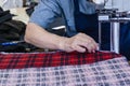 Female worker on a sewing manufacture uses electric cutting fabric machine. Textile industry, clothing production, fabric cutting Royalty Free Stock Photo