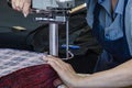 Female worker on a sewing manufacture uses electric cutting fabric machine. Textile industry, clothing production, fabric cutting Royalty Free Stock Photo