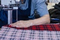 Female worker on a sewing manufacture uses electric cutting fabric machine. Textile industry, clothing production, fabric cutting Royalty Free Stock Photo