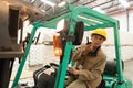Female worker talking on walkie-talkie while driving forklift in warehouse Royalty Free Stock Photo