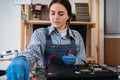 Female worker testing laptop motherboard using multimeter while working in repair computers service center. Royalty Free Stock Photo