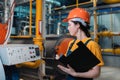 A female worker in uniform and helmet with a folder and a pen in her hand, writing meter readings. In the background-boiler room. Royalty Free Stock Photo