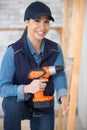 female worker using drill on wooden pieces