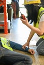 A female worker using a walkie-talkie called the factory`s first aid team to rescue an unconscious man Royalty Free Stock Photo