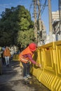 Female worker wearing orange overalls wearing a hard hat and wiping the construction site