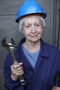 Female worker wearing uniform, blue hardhat and holding large adjustable wrench Royalty Free Stock Photo