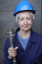 Female worker wearing uniform, blue hardhat and holding large adjustable wrench Royalty Free Stock Photo