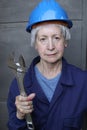 Female worker wearing uniform, blue hardhat and holding large adjustable wrench Royalty Free Stock Photo