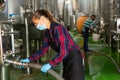 Female worker works at winery, filtering wine in barrels