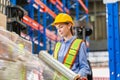 Female worker wrapping boxes in stretch film at warehouse, Worker wrapping stretch film parcel on pallet in factory warehouse